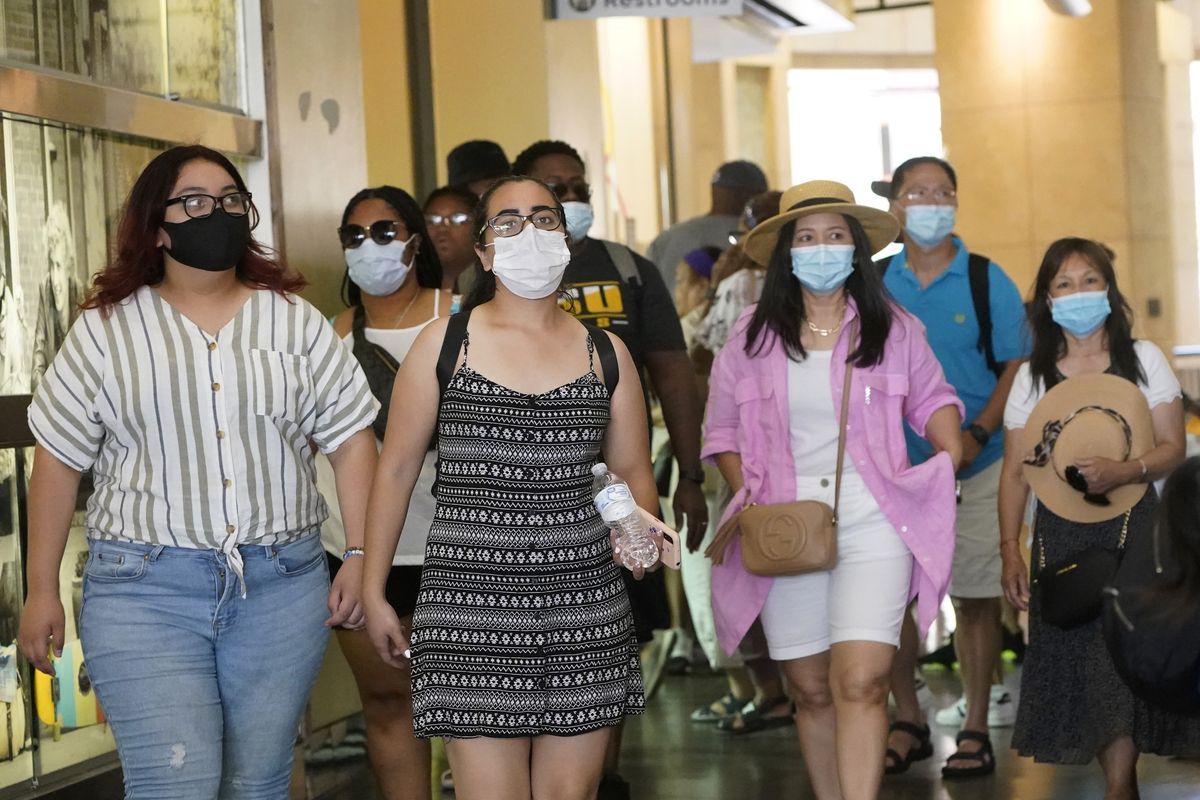 In this July 1, 2021 photo, visitors wear masks as they walk in a shopping district in the Hollywood section of Los Angeles. A rapid and sustained increase in COVID-19 cases in the nation