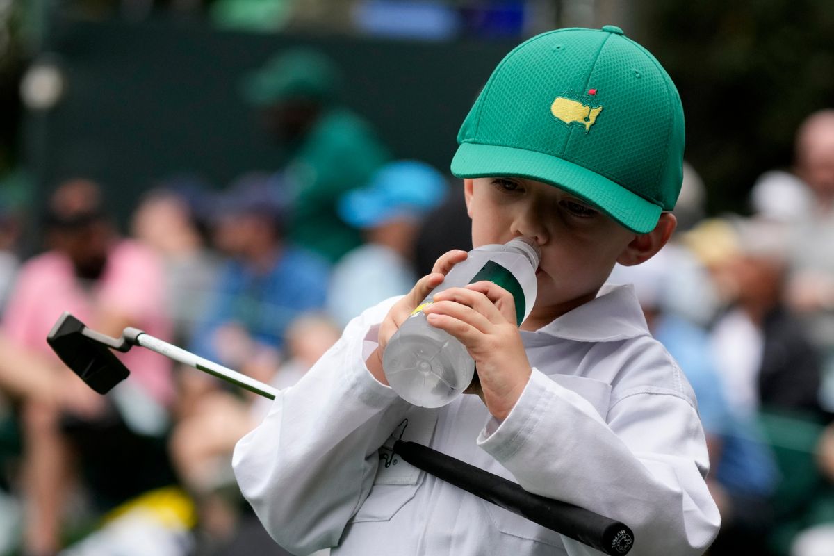 Mackenzie Hughes, of Canada's son Kenton drinks from a water bottle during the Par 3 contest at the Masters golf tournament on Wednesday, April 6, 2022, in Augusta, Ga.  (Charlie Riedel)