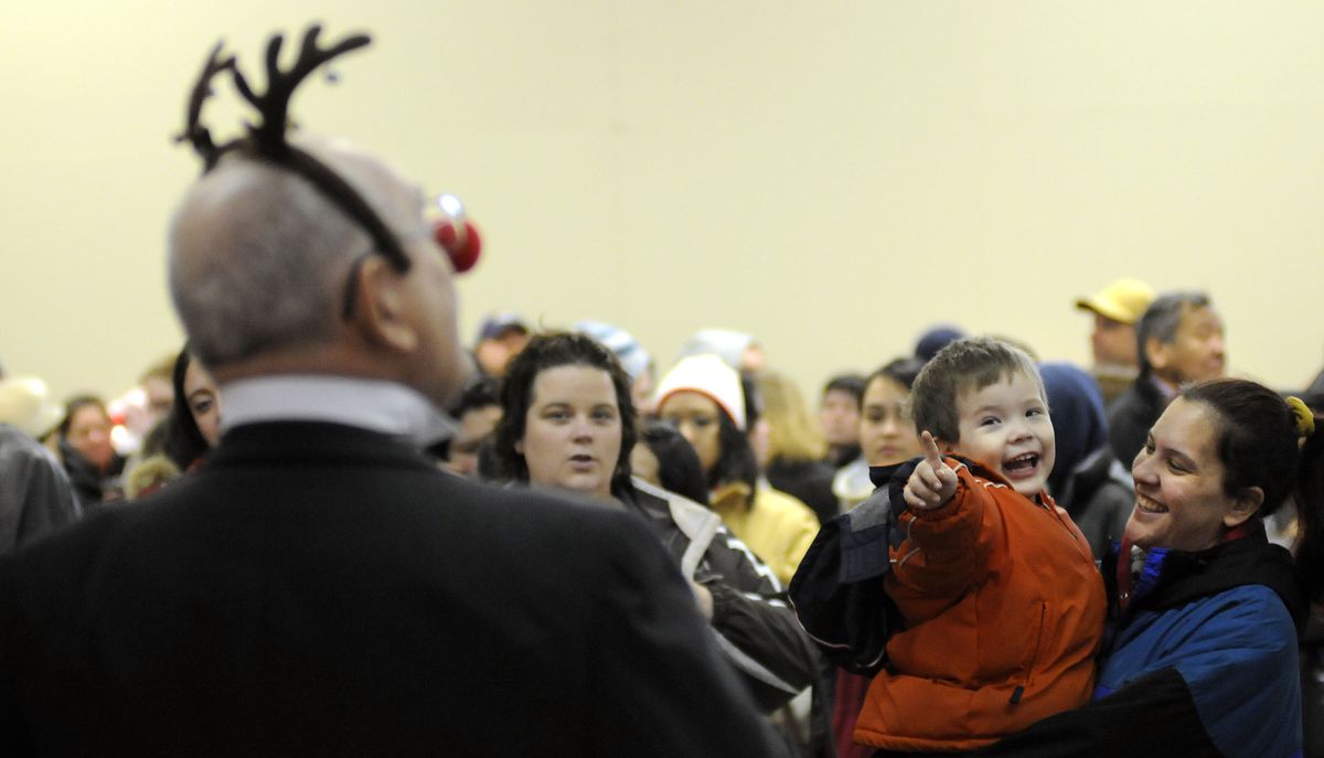 Chase Larson, 4, and his mother, Cathy Foster, enjoy the holiday sounds of Dick Townsend, left, and his group Inspiration as they sing "Rudolph the Red-Nosed Reindeer" to the long line of folks waiting at the Spokane County Fair & Expo Center for the Christmas Bureau