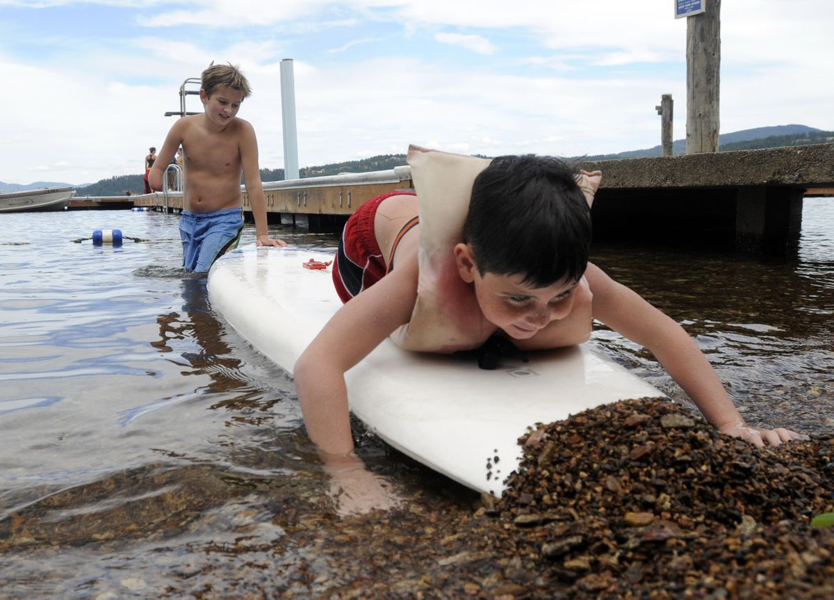 Kevin Nash, 7, of Rathdrum, digs his float board into the beach with the help of Matthew Ward, 12,  at Camp Cross on Lake Coeur d’Alene.  (Photos by JESSE TINSLEY / The Spokesman-Review)
