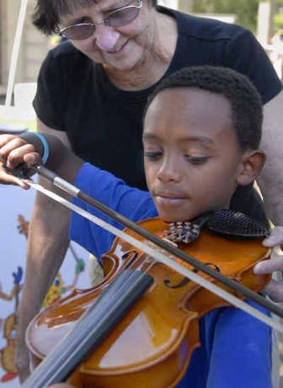 
Mikyas Noble, 7, of Spokane, plays the violin with help from Spokane Symphony volunteer Judy Fife on Saturday in Riverfront Park. 
 (Dan Pelle / The Spokesman-Review)