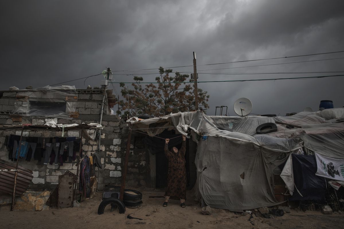 A Palestinian woman checks the nylon cover on the roof of her house on a rainy day in a poor neighborhood of Khan Younis, in the southern Gaza Strip, Wednesday, Jan. 20, 2021. (Khalil Hamra)