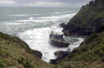
Waves crash up against an oil barge grounded in a rocky coastline cove below Cape Disappointment lighthouse near Ilwaco, Wash., on Monday. The barge, which broke loose and grounded on Saturday, is carrying no oil but has several thousand gallons of diesel fuel on board. 
 (Associated Press / The Spokesman-Review)