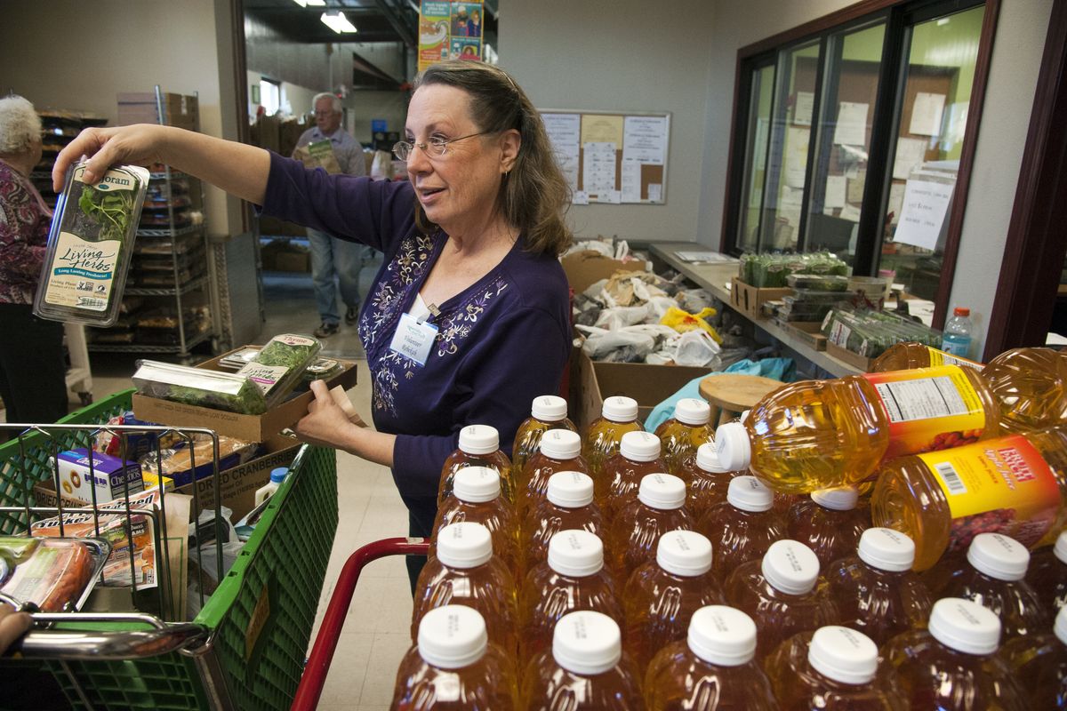 Spokane Valley Partners food bank volunteer Rebekah Fuller offers recipients fresh herbs, along with apple or orange juice, in the commodities section. (Dan Pelle)