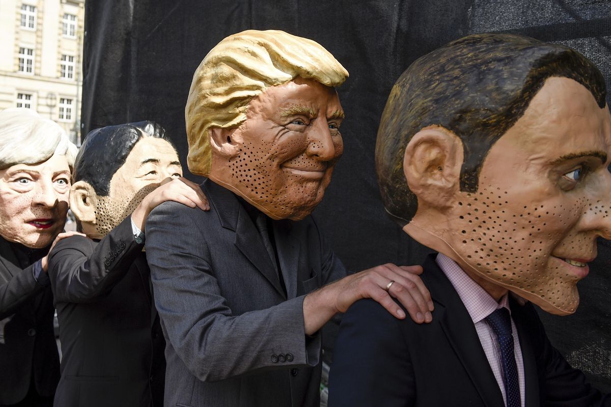 Demonstrators against the G20 Summit stand on stage wearing masks depicting, from left, British Prime Minister Theresa May, Japan’s Prime Minister Shinzo Abe, U.S. President Donald Trump and French President Emmanuel Macron, in Hamburg, Germany, Sunday, July 2, 2017. (Axel Heimken / Associated Press)