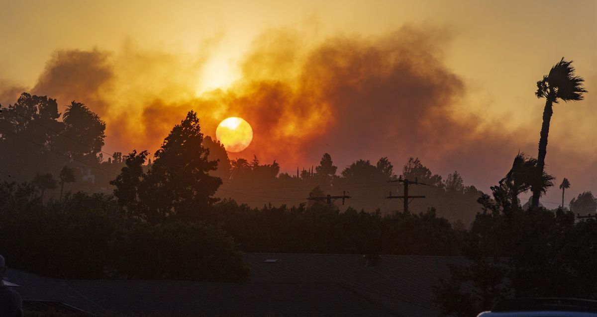 In this view from Newport Boulevard in North Tustin, the morning sun rises through the smoke of fire in the canyons east of North Tustin on Monday, Oct. 26, 2020. Firefighters were aggressively battling a vegetation fire that broke out in the hills near Silverado in Orange County as strong wind gusts pushed it. (Mark Rightmire)