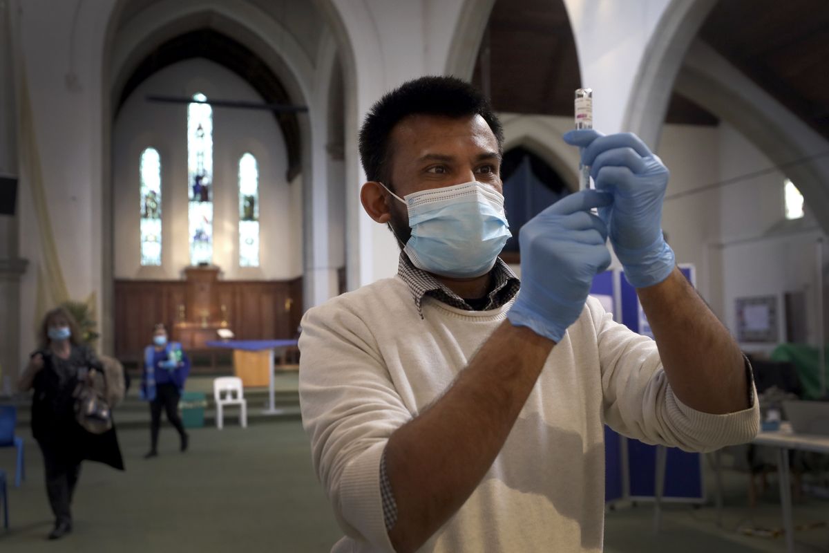Pharmacist Rajan Shah prepares a syringe of the AstraZeneca vaccine at St John