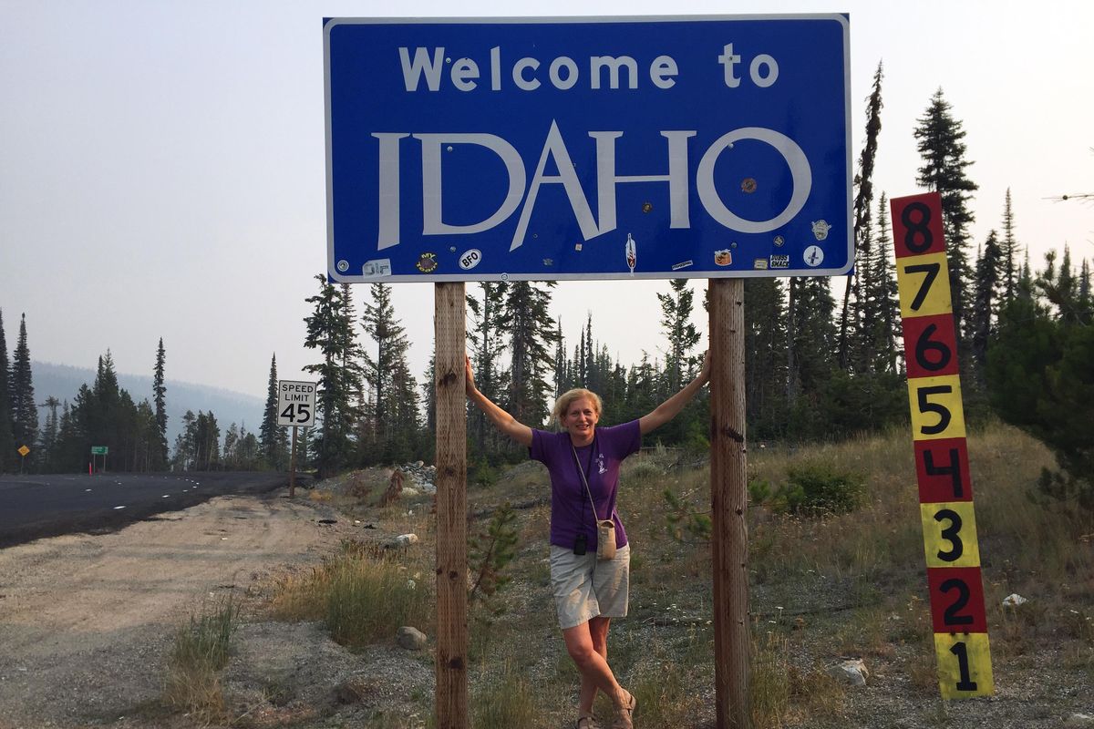 Associated Press Travel Editor Beth Harpaz stands beneath a “Welcome to Idaho” sign near Gibbonsville, and the Montana border in September. Idaho was Harpaz’s final destination on a quest to visit all 50 states. (Elon Harpaz/Associated Press)