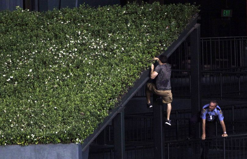 A fan eludes a police office by climbing onto the center field wall after running across the outfield and stopping play during the ninth inning of a baseball game between the Houston Astros and New York Mets Friday, May 13, 2011, in Houston.  The Mets beat the Astros 6-4. (David Phillip / Associated Press)