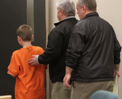 The 9-year-old boy accused of accidentally shooting a classmate is led away after his juvenile detention hearing in Kitsap County on Thursday. (Associated Press)