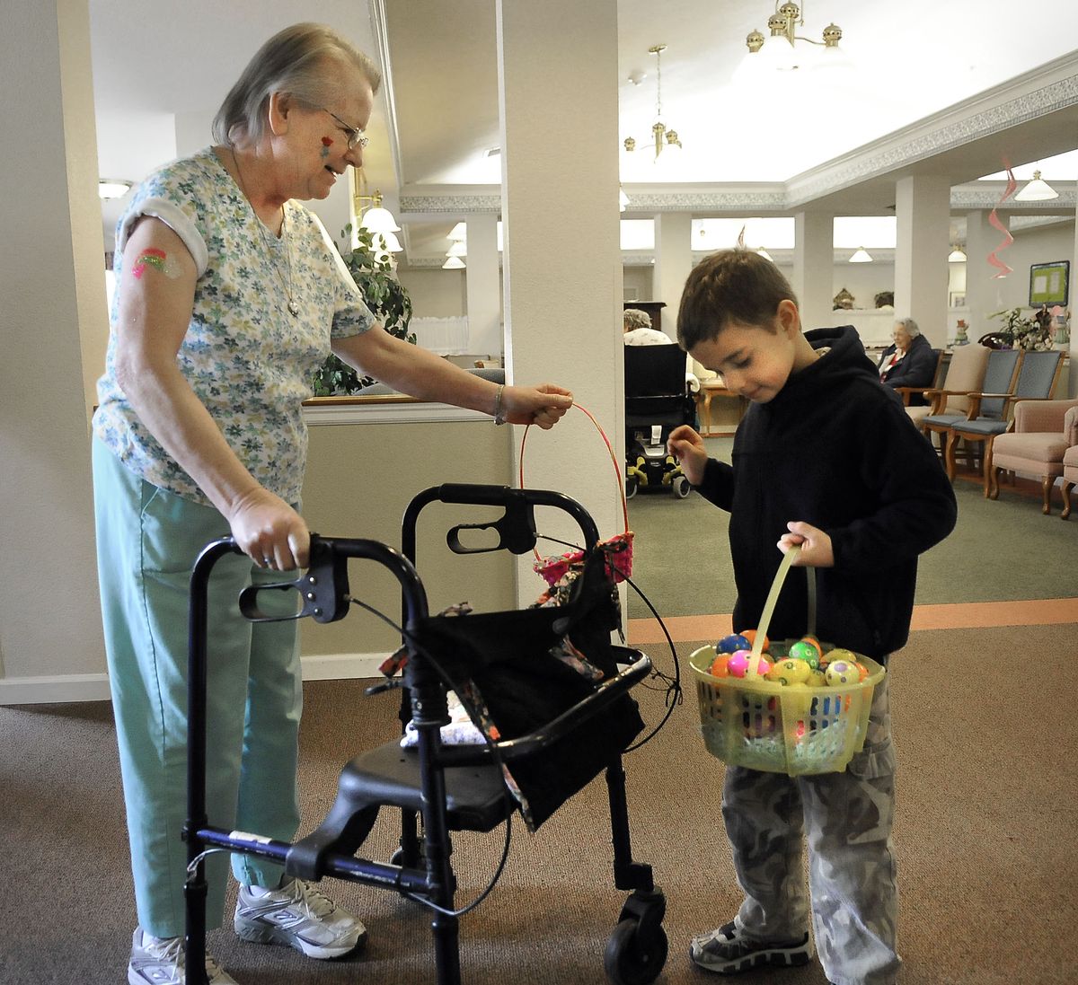 Sam Kiperash, 7, shares Easter eggs from his basket with Charlotte Carpenter, 59, on Saturday at the Windriver House in Spokane. Sam had already toured  the hallways and gathered the eggs before Carpenter started out with her empty basket.  (Photos by DAN PELLE / The Spokesman-Review)