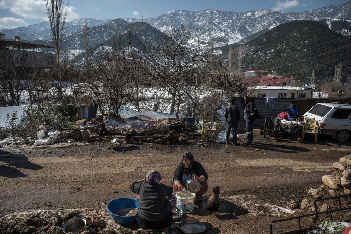 Women wash dishes on the side of the road next to their house that was damaged by the earthquake in the Kayabasi village, Turkey, on Feb. 11. Across southern Turkey, earthquake survivors who have been sleeping outside – unable to go home, or unwilling to risk staying inside amid fears of aftershocks – remain in need of shelter, blankets and toilets.  (SERGEY PONOMAREV/New York Times)