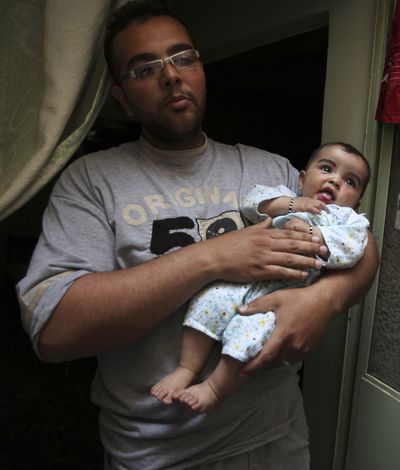 Asad Raad holds a baby boy he rescued from a car bombing in Baghdad on Tuesday. The motorbike salesman pulled the child from a car ignited in the explosion.  (Associated Press / The Spokesman-Review)