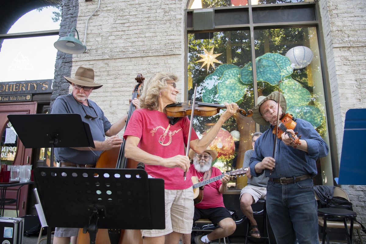 Fiddlers Janet Shelby, center, and Paul Essex, right,, along with bass player Jon Shelby, left, play with the group Ludiker Music performs outside of O’Doherty’s restaurant on Spokane Falls Boulevard in downtown Spokane Monday, June 14, 2021. The group will perform again at Street Music Week, which runs through Friday in the downtown Spokane area.  (Jesse Tinsley/The Spokesman-Review)