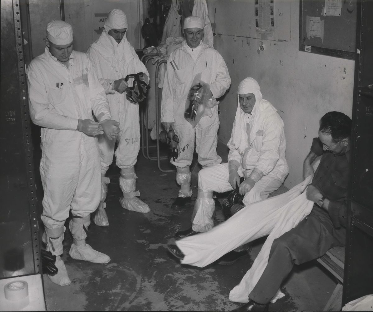 A photo provided May 21, 1957, by the General Electric Co. shows workers at the Hanford plutonium plant  putting on protective clothing before entering radiation zones or areas where radioactive contamination (dust, liquids, etc.) is known or suspected to exist. Some of these areas only require shoe covers and lab coats; others may require gloves, coveralls, masks, rubbers and hoods, according to GE. (General Electric Company / The Spokesman-Review archive)
