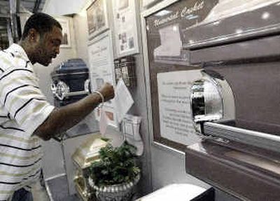 
Kyle Green reads information about the six models of caskets made by the Universal Casket Co. at Costco Wholesale in Chicago on Monday.
 (AP / The Spokesman-Review)