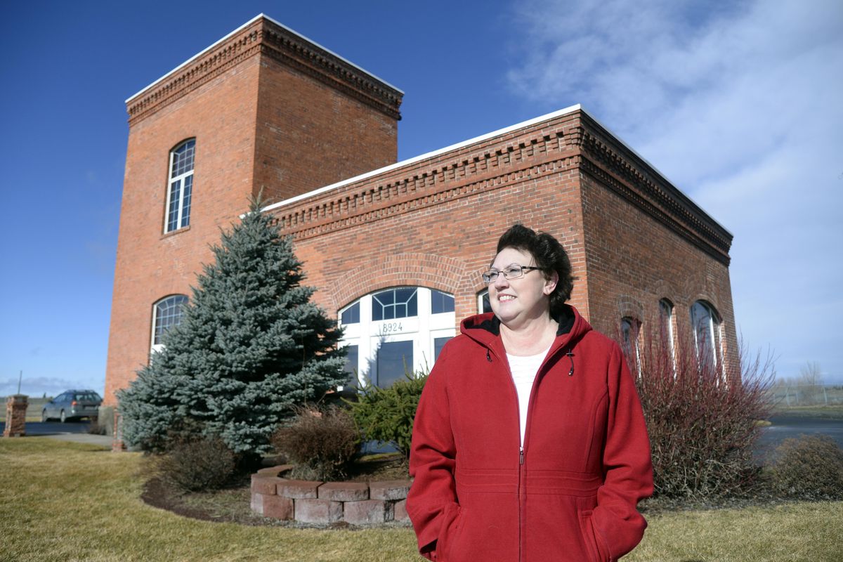 Donna Tatman, who lived on the West Plains for more than 30 years, stands Thursday in front of the former train station that sits by itself by the Spokane International Airport. She and others, especially those whose families lived in the area, would like  to see the building, which now belongs to the Spokane Airport, preserved for its historical value. (Jesse Tinsley / The Spokesman-Review)