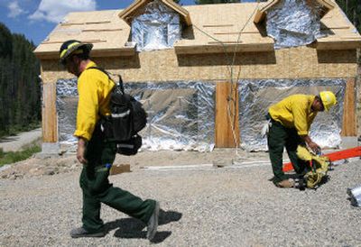 A firefighting crew from North Carolina prepares to move on to work on other structures after fire wrapping a home and installing a sprinkler system on a property near Bonanza, Idaho, on Wednesday. Firemen are attempting to protect structures from the Potato fire, which is burning near the mountain community.
(Associated Press / The Spokesman-Review)