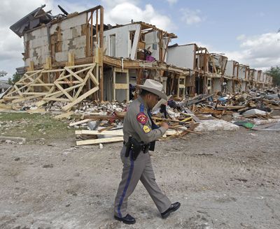Texas Department of Public Safety Sgt. Jason Reyes walks past a damaged apartment complex Sunday in West, Texas. (Associated Press)