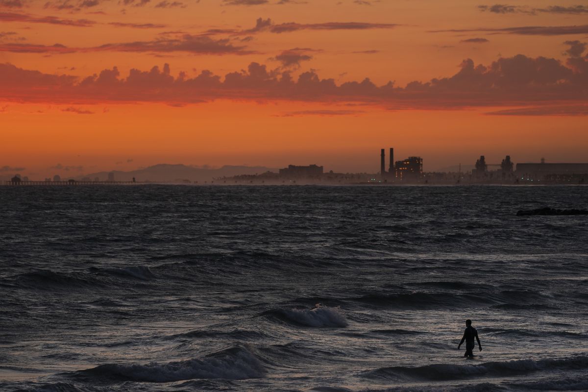 A man wades into the ocean at sunset, Tuesday, June 22, 2021, in Newport Beach, Calif. In a report released Wednesday, Dec. 8, 2021, the National Academy of Sciences says to fight climate change the world needs to look into the idea of making the oceans suck up more carbon dioxide.  (Jae C. Hong)
