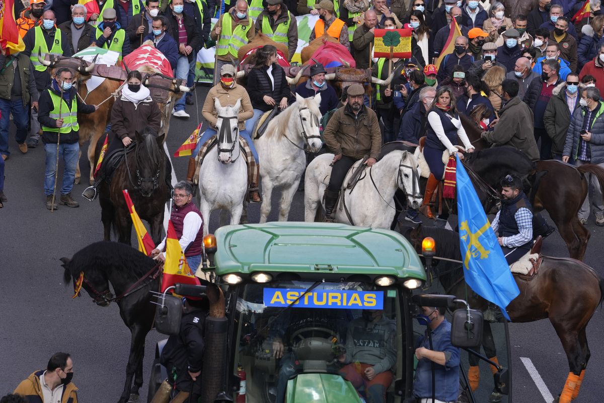 People on horseback follow a tractor during a march in defence of Spanish rural areas during a protest in Madrid, Spain, Sunday, Jan. 23, 2022. Members of rural community are demanding solutions by the government for problems and crisis in the Rural sector.  (Paul White)