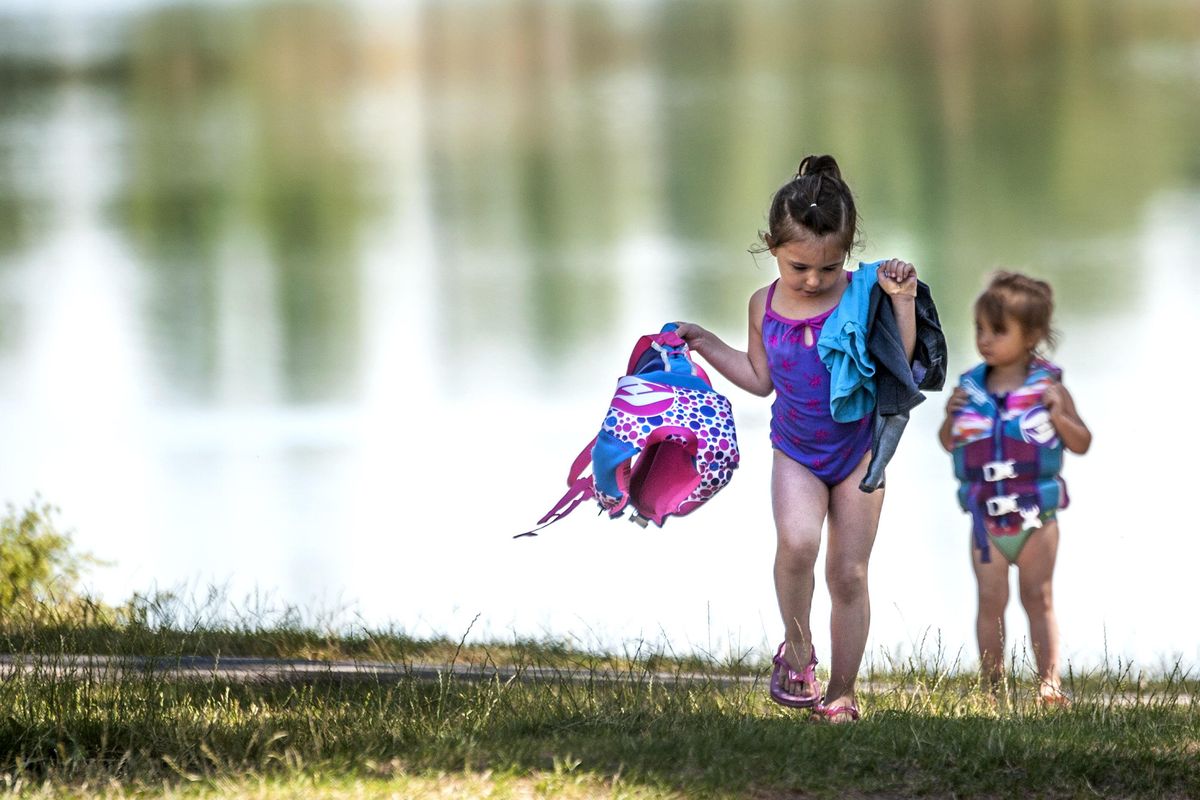 Keturah Al-Sweedy, 3, left, and her sister Myra, 2, walk away from Medical Lake after a morning swim. (Kathy Plonka / The Spokesman-Review)