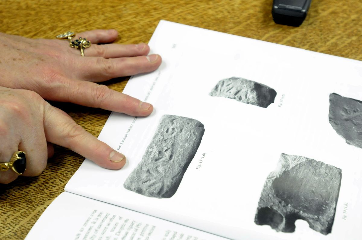 Professor Georgia Bonny Bazemore points out some artifacts from one of her recent publications to show the significant artifacts and inscriptions that she and her team found in the Rantidi forest in Cyprus.  (Jesse Tinsley / The Spokesman-Review)