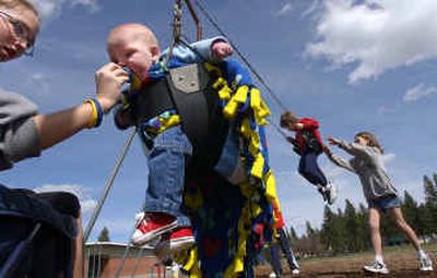 
Halie Gonwick, 13, gives 7-month-old Daxton Larson his pacifier while Bo Gonwick, 11, pushes Dakota Larson, 5, on the swings Tuesday at the playground at University Elementary School in Spokane Valley.
 (Liz Kishimoto / The Spokesman-Review)