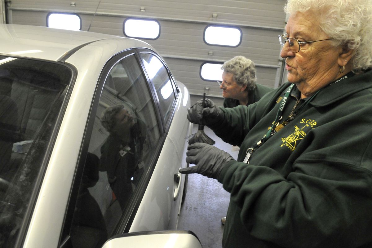 SCOPE volunteer Donna Goff, far right, prepares fingerprint powder for a crime victim’s car Monday while Rhonda Gore looks for fingerprints at the Spokane Valley police headquarters at 12710 E. Sprague Ave. (Jesse Tinsley)