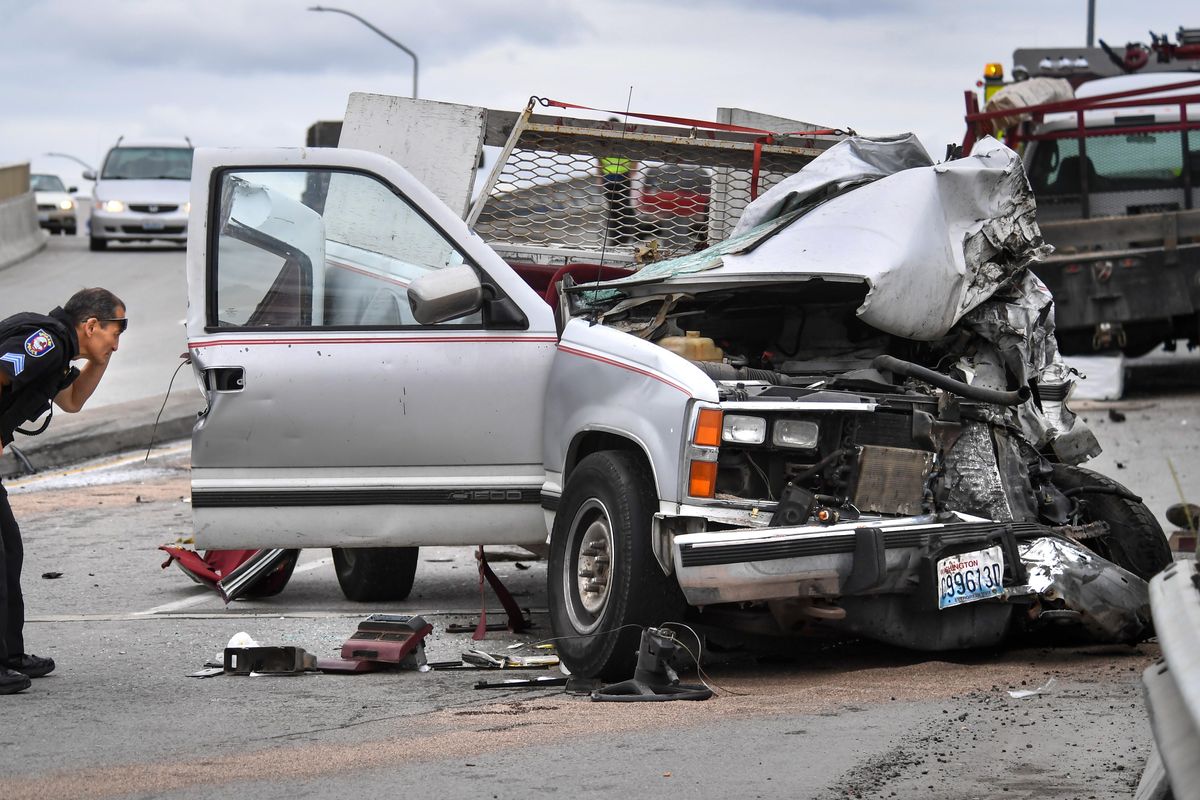 Spokane Police Sgt. Sam Yamada views the damage to the cab of a pickup that caused a four-car crash, Friday morning, June 21, 2019, on the Freya Way Bridge in Spokane. The driver of the truck was extricated from the vehicle. (Dan Pelle / The Spokesman-Review)