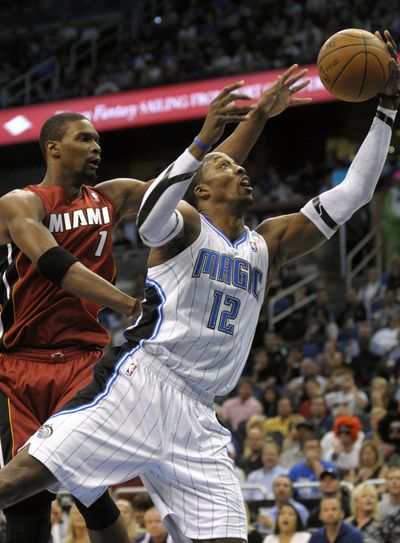 Orlando’s Dwight Howard, grabbing an offensive rebound in front of Miami’s Chris Bosh, had 24 points and 25 rebounds. (Associated Press)