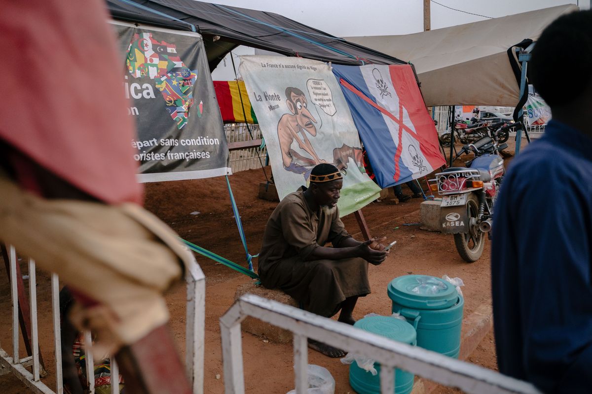 A man sits on Oct. 15 in front of anti-France banners in Niamey, Niger.  (Carmen Yasmine Abd Ali/For The Washington Post)