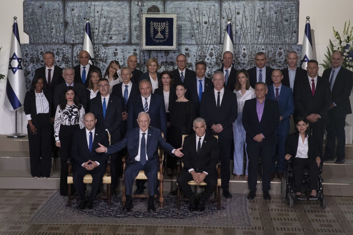 Israeli Prime Minister Naftali Bennett, seated left, President Reuven Rivlin, seated center, and Alternate Prime Minister and Minister of Foreign Affairs Yair Lapid seated right, pose for a group photo with the ministers of the new government at the President