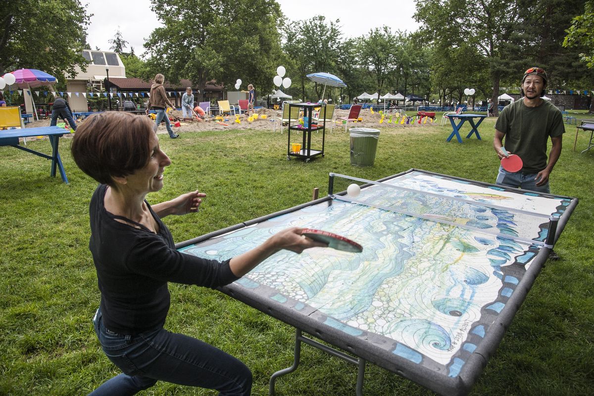 Ellen Picken returns a ping pong ball to Toshi Takekoshi as they play on a table created by local artist Loretta West in the Gondola Meadow, July 8, 2016, in Riverfront Park. A kickoff celebration for construction of the park’s renovation also included a beer garden, live music, and a field of ping pong tables and a 30-ton sandbox. An ice ribbon skating rink is planned for the area of the sandbox. (Dan Pelle / The Spokesman-Review)