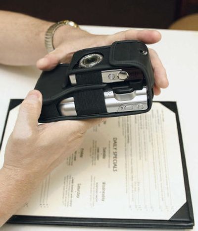 
Tommy Craig's hands hold the reader, a device that reads print aloud for the blind, as he sits with a restaurant menu on Thursday. 
 (Associated Press / The Spokesman-Review)