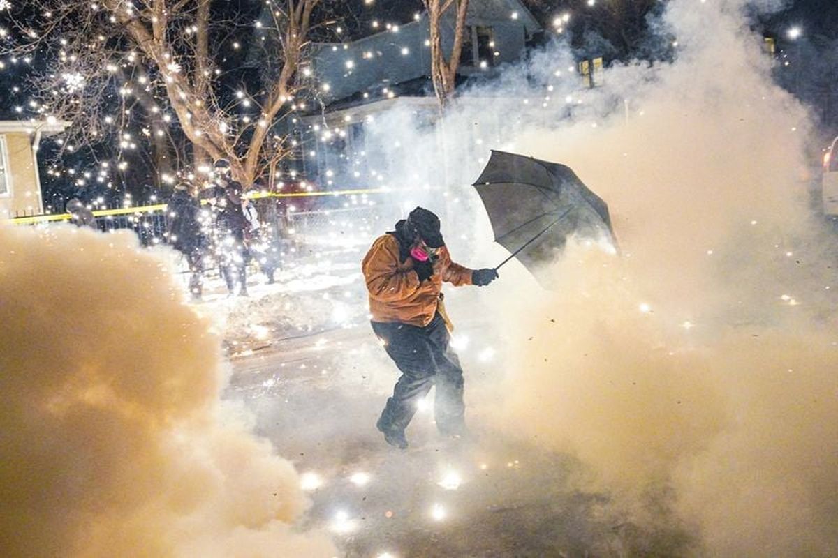 A protesting community member attempts to protect themselves as federal agents fire munitions and pepper balls, as tensions rise after federal law enforcement agents were involved in a shooting incident, a week after a U.S. Immigration and Customs Enforcement (ICE) agent fatally shot Renee Nicole Good, in north Minneapolis, Minnesota, U.S., January 14, 2026.  (Ryan Murphy)