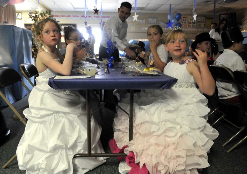 Third-graders Audrina Gainey, left, and Stephanie Sawchuk, right, wear ball gowns and munch on a lunch served by parents and teachers May 24, at Sunrise Elementary. The event, called the Fairy Tale Ball, was a time to dress up and practice proper dining etiquette. (Jesse Tinsley)