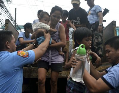 Residents living near the slopes of Mayon volcano are evacuated to public schools Thursday by police in anticipation of the powerful typhoon Haiyan that threatened several provinces in central Philippines. (Associated Press)