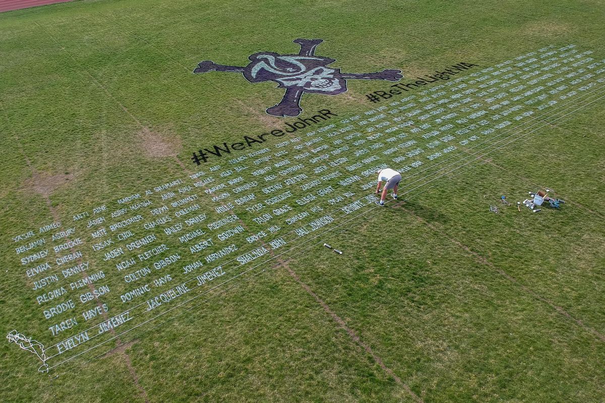 Art teacher Tom Pettoello paints the names of every graduating senior on the football field at Rogers High School Friday, April 17, 2020 to honor the senior class whose final year of high school was cut short by the order to stay home because of COVID-19. (Jesse Tinsley / The Spokesman-Review)