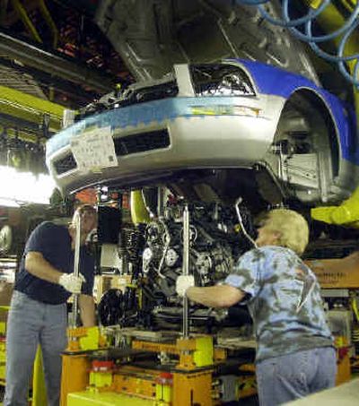 
Assemblyline workers at the AutoAlliance International plant in Flat Rock, Mich., install an engine Monday in the new 2005 Ford Mustang. 
 (Associated Press / The Spokesman-Review)