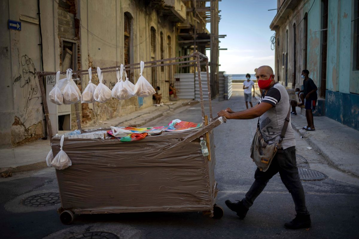 A street vendor wearing a mask as a precaution against the spread of the new coronavirus pushes his cart down a street in Havana, Cuba, Monday, Aug. 31, 2020. Cuban authorities will introduce new measures starting tomorrow Tuesday aimed at containing the spread of the coronavirus in Havana among others a curfew from 7 pm until 5 am and no one without special permission will be able to enter or leave the province. The new measures will last at least 15 days.  (Ramon Espinosa)