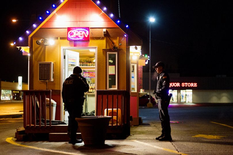 Jason Hunt, officer with the Post Falls Police Department, right, looks on as Coeur d'Alene Police Department's Sgt. Brett Walton takes a phone call Wednesday night while investigating the scene of an armed robbery of the Lean Bean coffee stand on Sherman Avenue. Hunt and his K-9 were called to aid in the search for the suspect who fled on foot. (Shawn Gust/press)