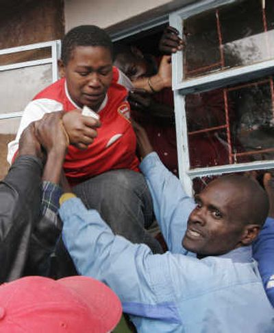 
A woman is helped out of a window to escape being crushed at a polling station Thursday in the slum of Kibera, Kenyan presidential challenger Raila Odinga's main constituency in Nairobi.Associated Press
 (Associated Press / The Spokesman-Review)