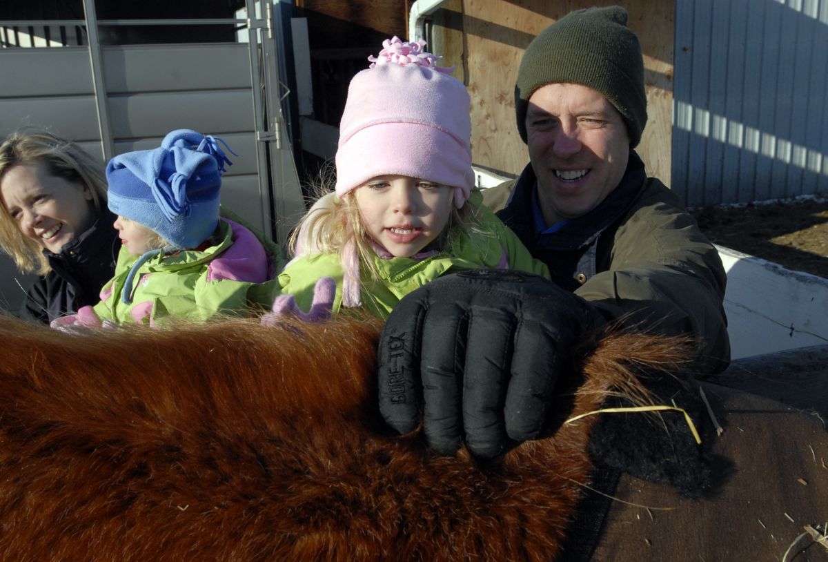Piper Wasson is held by her dad, Steve, as she pets Dusty for the first time. (J. Rayniak / The Spokesman-Review)