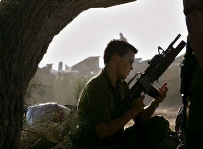 
An Israeli soldier cleans his weapon at a gathering point near Kibbutz Mefalsim in southern Israel on Monday. 
 (Associated Press / The Spokesman-Review)