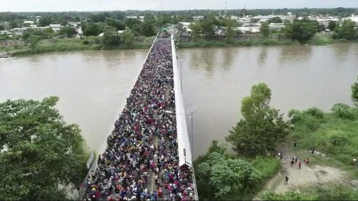 This Oct. 19, 2018 frame grab from video provided by Televisa, shows migrants bound for the U.S.-Mexico border waiting on a bridge that stretches over the Suchiate River, connecting Guatemala and Mexico, in Tecun Uman, Guatemala. The gated entry into Mexico via the bridge has been closed. The U.S. president has made it clear to Mexico that he is monitoring its response. On Thursday he threatened to close the U.S. border if Mexico didn’t stop the caravan. (AP)
