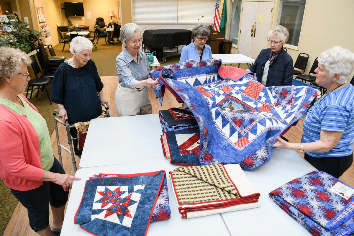 Members of the quilting group at Fairwood Retirement Village, from left, Peggy Ann Jones, Doris Cummins, Joan Nelson, Judy McCorkle, Dorothy Lochhead and Mogie Sabine look at some of the quilts they produced to give to World War II veterans as part of the Quilts of Valor program, shown Thursday, May 17, 2018. (Jesse Tinsley / The Spokesman-Review)