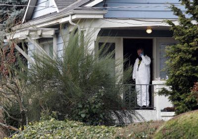 
A crime scene investigator stands Sunday in the doorway of the house where a gunman killed six people before killing himself Saturday morning. 
 (Associated Press / The Spokesman-Review)