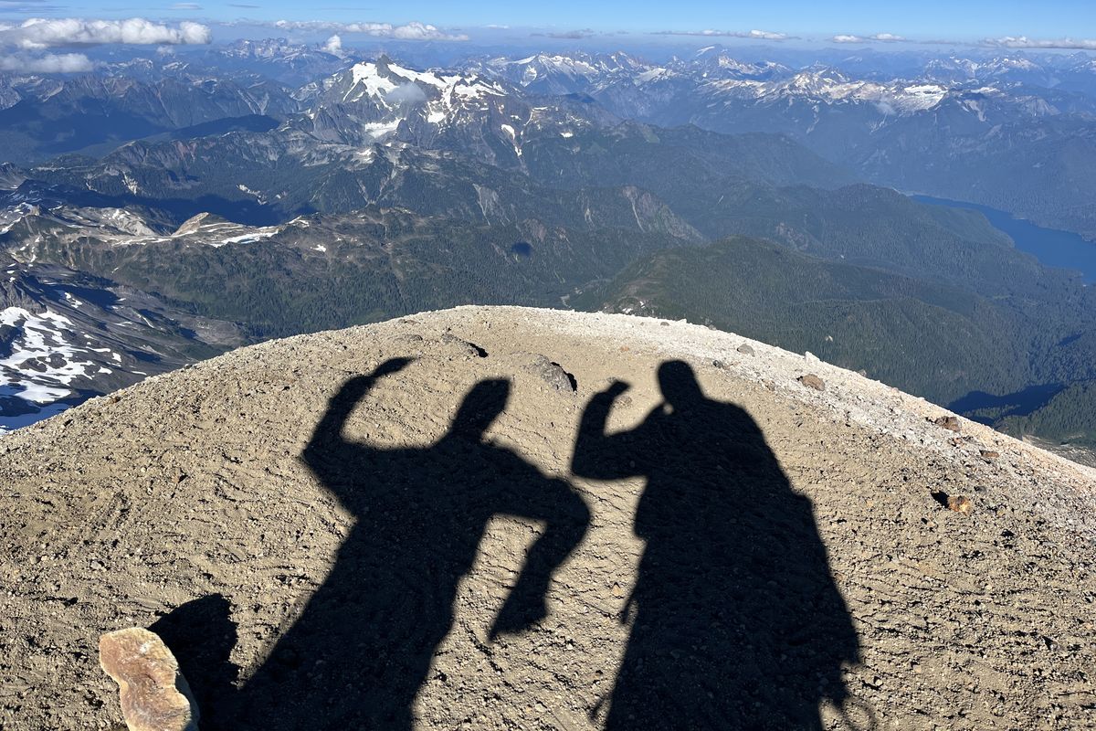 At left: Marc McPherson navigates a snow-covered slope on Mount Rainier. At right: The shadows of Marc McPherson, left, and Nick Burson on the summit of Mount Baker on Aug. 2. Baker was the last of 12 peaks in the Cascade Range that the pair climbed over 10 days.  (Courtesy of Nick Burson)