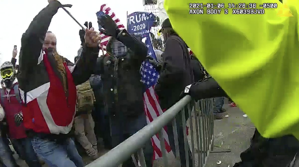This still frame from Metropolitan Police Department body worn camera video shows Thomas Webster, in red jacket, at a barricade line at on the west front of the U.S. Capitol on Jan. 6, 2021, in Washington. Webster, a Marine Corps veteran and retired New York City Police Department Officer, is accused of assaulting an MPD officer with a flagpole. A number of law enforcement officers were assaulted while attempting to prevent rioters from entering the U.S. Capitol. (HOGP)